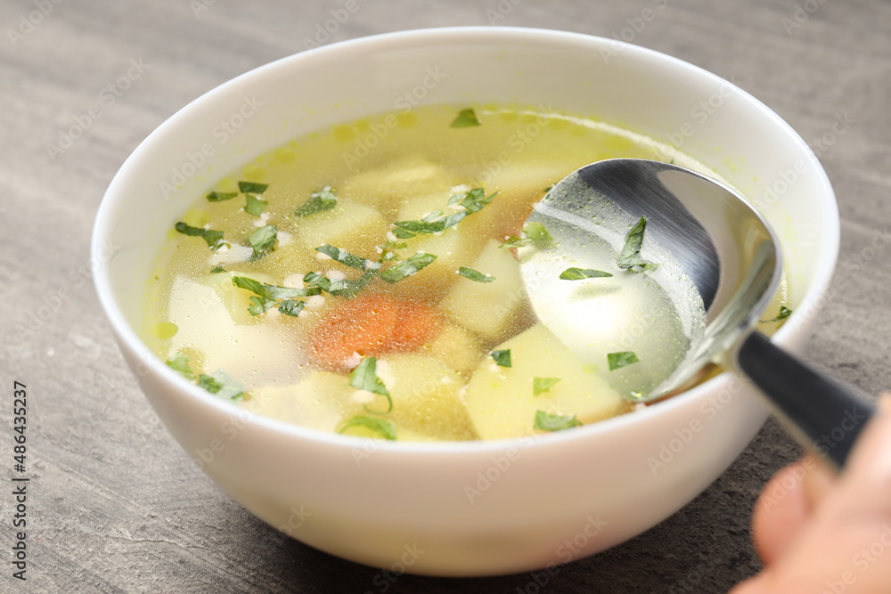 Concept of tasty food with chicken soup on gray textured background Concept of tasty food with chicken soup on gray textured background