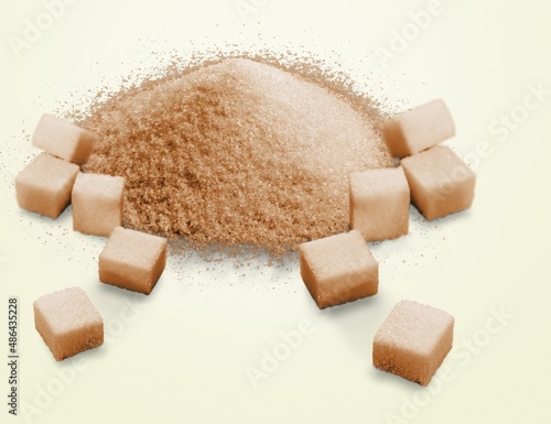 Pile of brown granulated sugar and sugar cubes on the desk