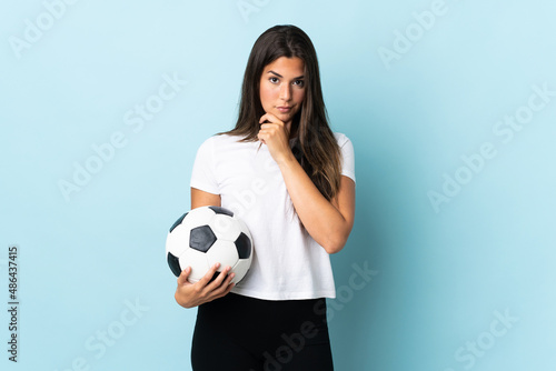 Young football player brazilian girl isolated on blue background thinking © luismolinero