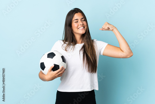 Young football player brazilian girl isolated on blue background doing strong gesture