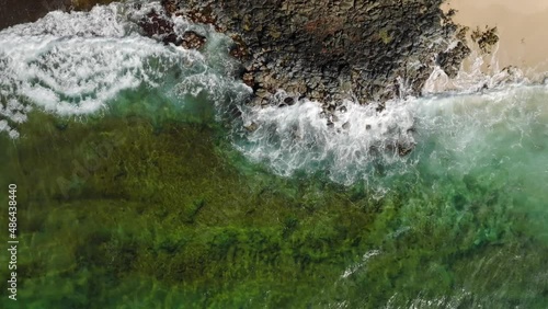 Wide Aerial Birds Eye view moving downwards at Shipwreck Beach, Hawaii. Ocean waves crashing on rocks and beach. photo