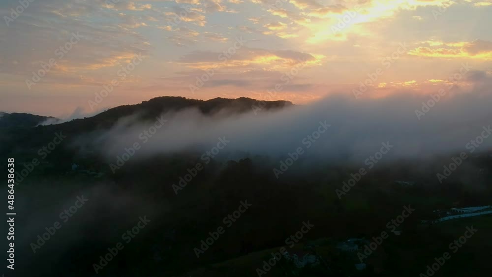 Sunset over a mountain peak with clouds hanging in front Sunset over a mountain peak with clouds hanging in front