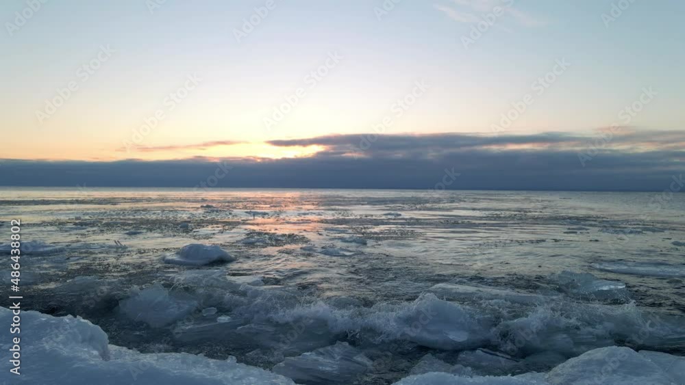 Waves crashing on the shore on a winter morning, icebergs ice formations floting on the water Waves crashing on the shore on a winter morning, icebergs ice formations floting on the water