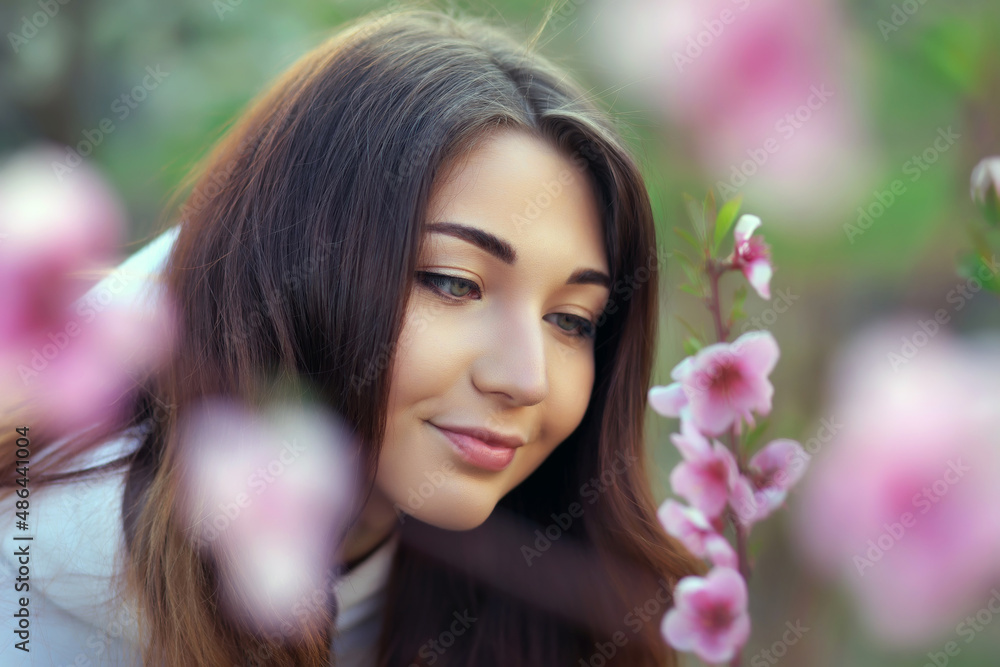 Smiling beautiful girl standing near a peach tree during sunset. Happy face. Spring time. Smiling beautiful girl standing near a peach tree during sunset. Happy face. Spring time.