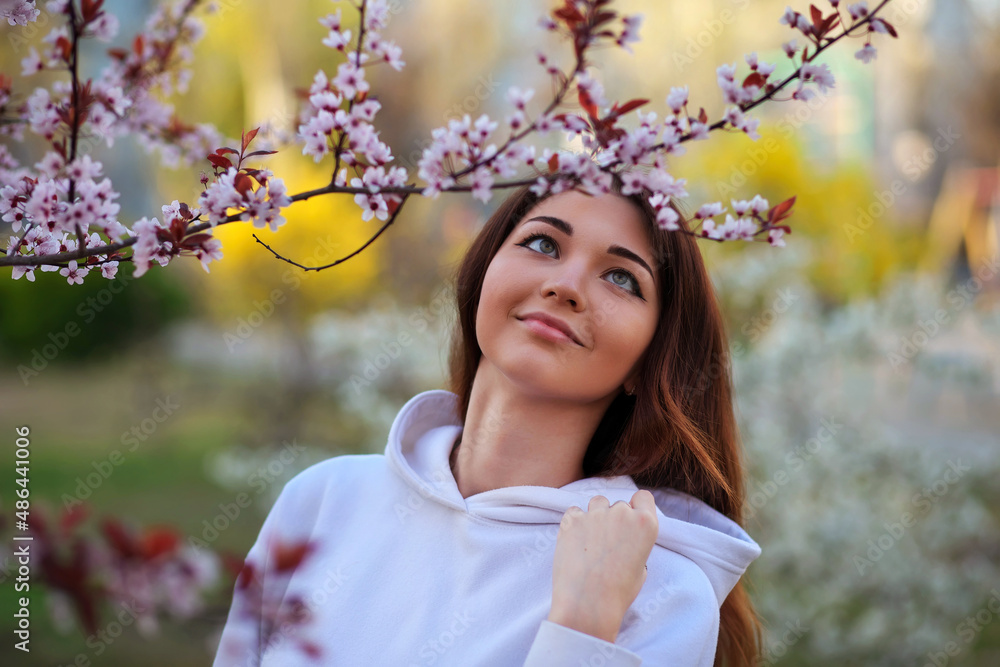 Smiling beautiful girl standing near a peach tree during sunset. Happy face. Spring time. Smiling beautiful girl standing near a peach tree during sunset. Happy face. Spring time.