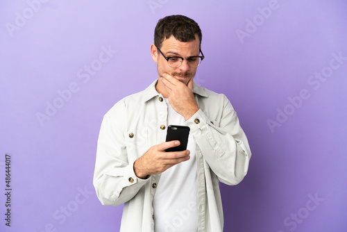 Brazilian man over isolated purple background thinking and sending a message © luismolinero