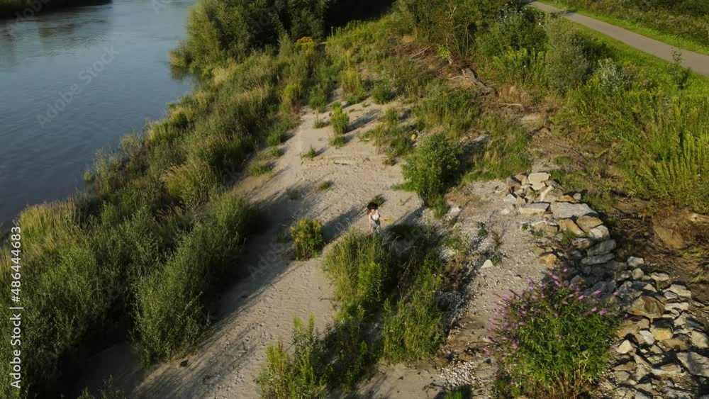 A girl with a cowboyhat picking flowers next to a river. A girl with a cowboyhat picking flowers next to a river.