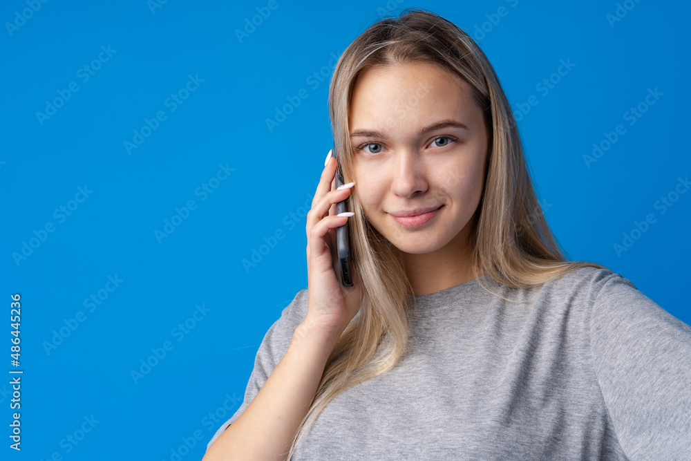 Pretty teenage girl talking on the mobile phone against blue background Pretty teenage girl talking on the mobile phone against blue background