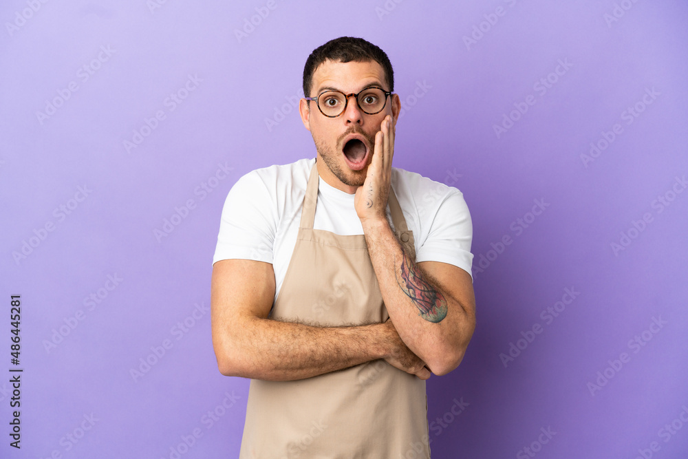 Brazilian restaurant waiter over isolated purple background surprised and shocked while looking right