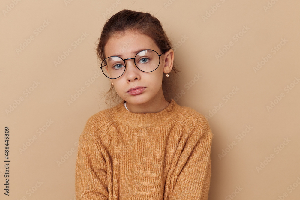 Portrait of happy smiling child girl in a sweater and posing glasses isolated background