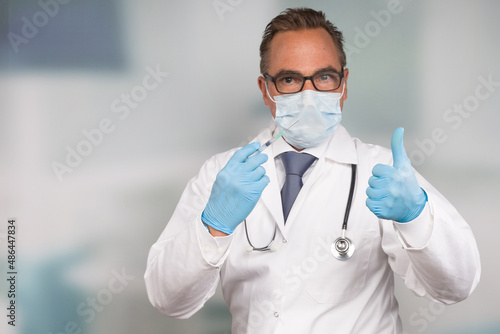 male doctor wearing a medical face mask and medical gloves shows thumbs up