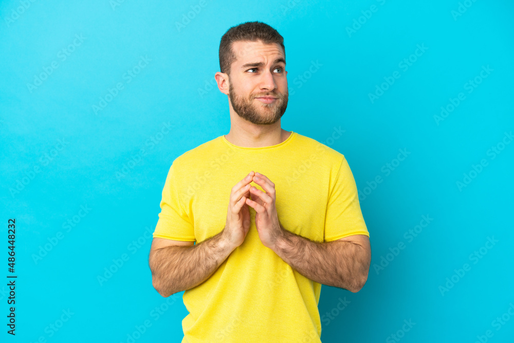 Young handsome caucasian man isolated on blue background scheming something Young handsome caucasian man isolated on blue background scheming something