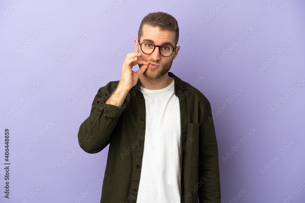 Young handsome caucasian man isolated on purple background showing a sign of silence gesture Young handsome caucasian man isolated on purple background showing a sign of silence gesture