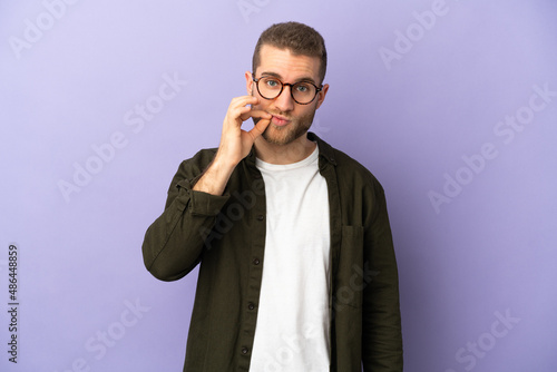 Young handsome caucasian man isolated on purple background showing a sign of silence gesture