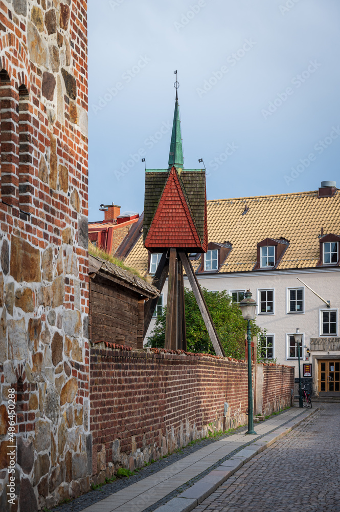 Obraz premium Steeple and old stone buildings along a cobblestoned street in the city center of Lund Sweden
