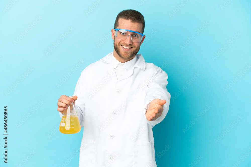 Young caucasian scientific man isolated on blue background shaking hands for closing a good deal