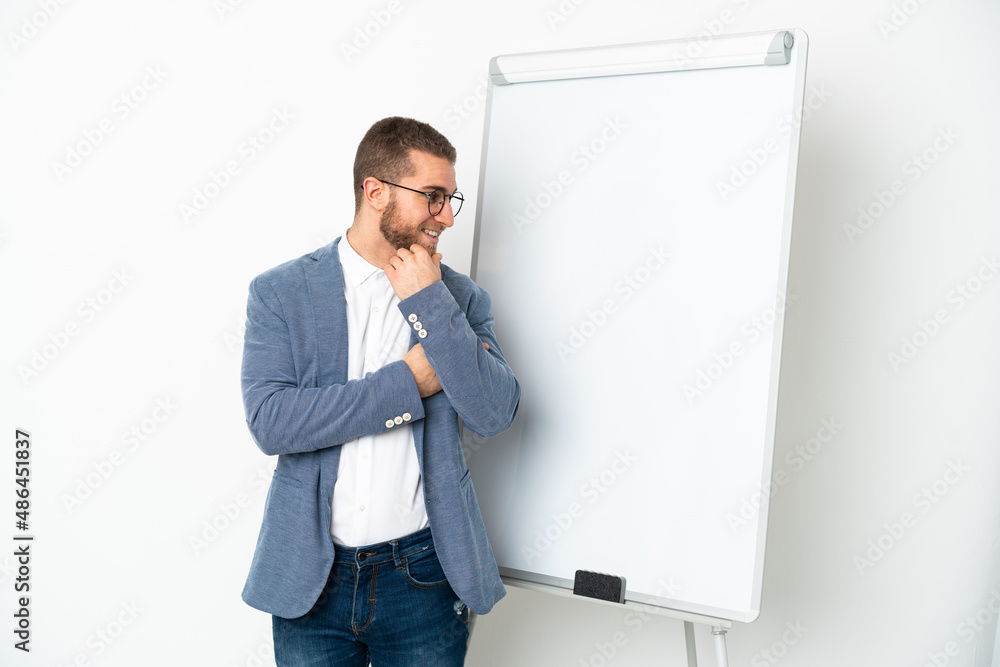 Young handsome caucasian man isolated on white background giving a presentation on white board and looking side Young handsome caucasian man isolated on white background giving a presentation on white board and looking side