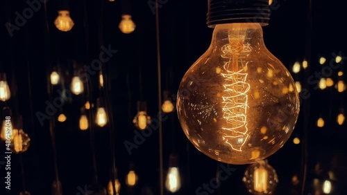 Flickering old fashion tungsten Edison light bulb lamp over black background. Slow motion shot 4K.