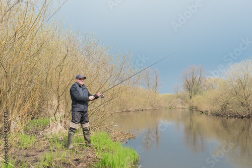 Fisherman with a fishing rod on the river bank.