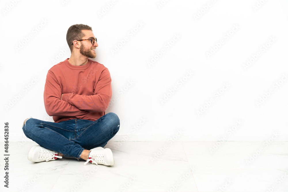 Young handsome man sitting on the floor happy and smiling Young handsome man sitting on the floor happy and smiling