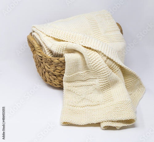 White merino wool knitted blanket in geometric pattern in basket on white background
