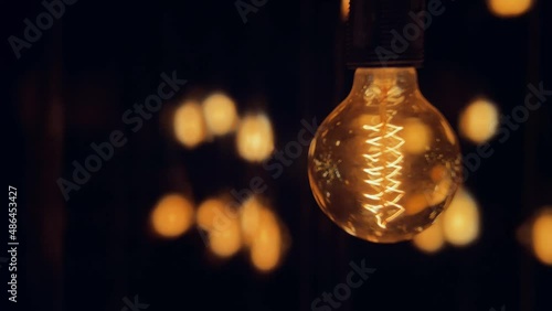 Flickering old fashion tungsten Edison light bulb lamp over black background. Slow motion shot 4K.