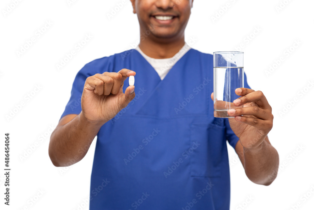 healthcare, profession and medicine concept - close up of happy smiling doctor or male nurse in blue uniform with pill and glass of water over white background healthcare, profession and medicine concept - close up of happy smiling doctor or male nurse in blue uniform with pill and glass of water over white background