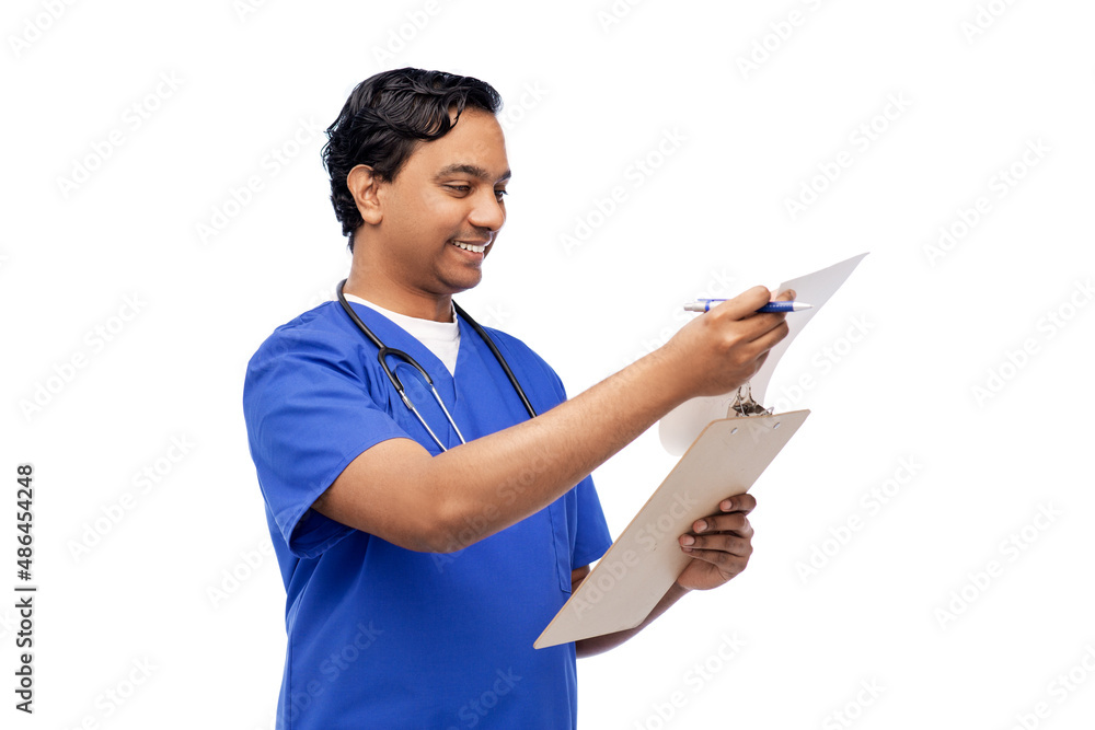 healthcare, profession and medicine concept - happy smiling indian doctor or male nurse in blue uniform writing medical report on clipboard over white background healthcare, profession and medicine concept - happy smiling indian doctor or male nurse in blue uniform writing medical report on clipboard over white background