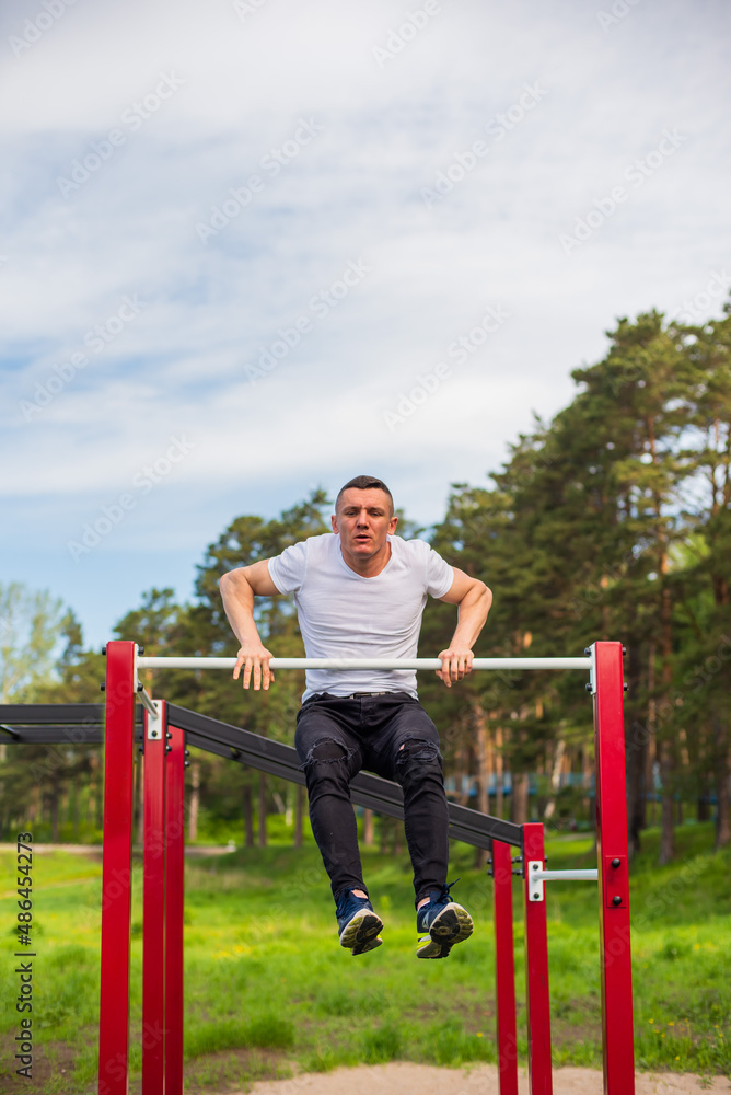 Caucasian man pulls himself up on a horizontal bar on a sports ground. Caucasian man pulls himself up on a horizontal bar on a sports ground.