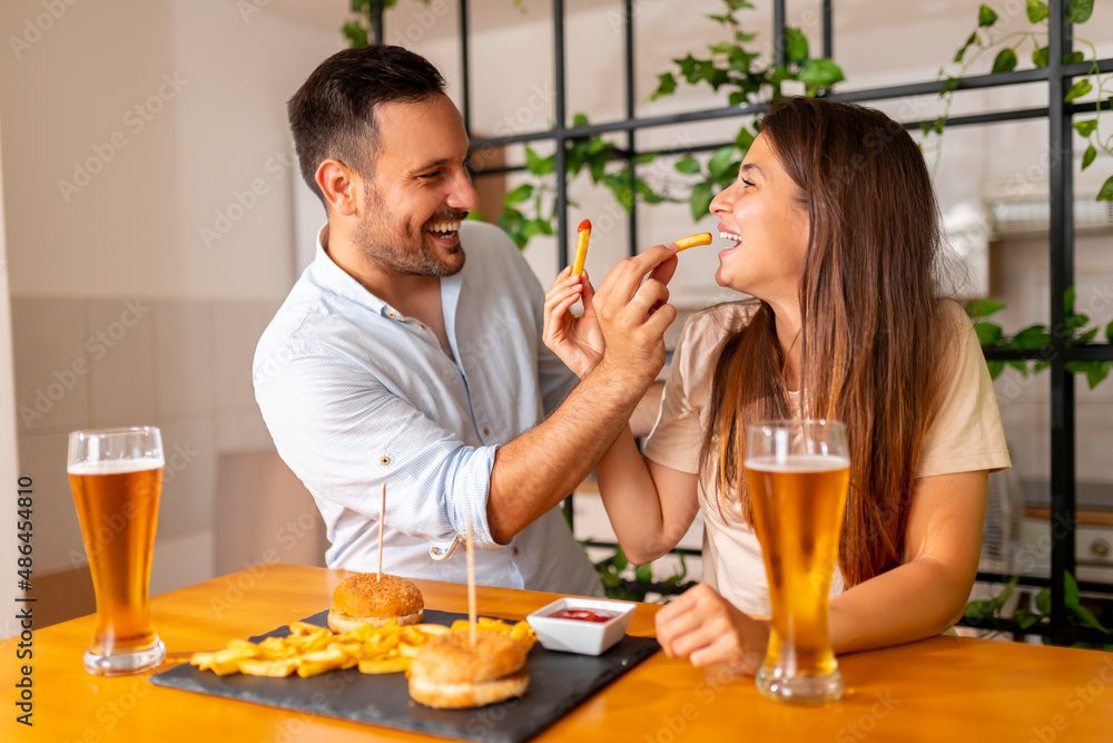Couple having fun eating burgers and drinking beer Couple having fun eating burgers and drinking beer