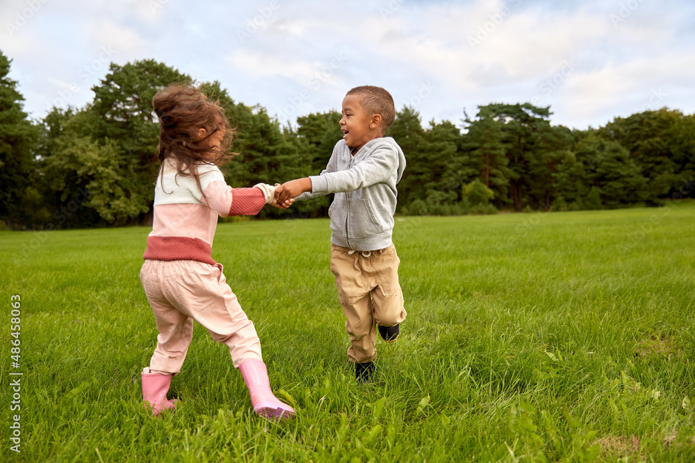 childhood, leisure and people concept - happy smiling little boy and girl having fun at park childhood, leisure and people concept - happy smiling little boy and girl having fun at park