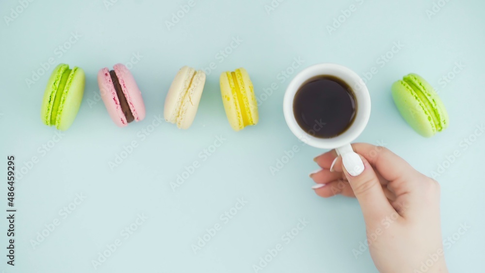 Top view of multicolored French Macarons cookies and a cup of coffee on a pastel blue background Top view of multicolored French Macarons cookies and a cup of coffee on a pastel blue background