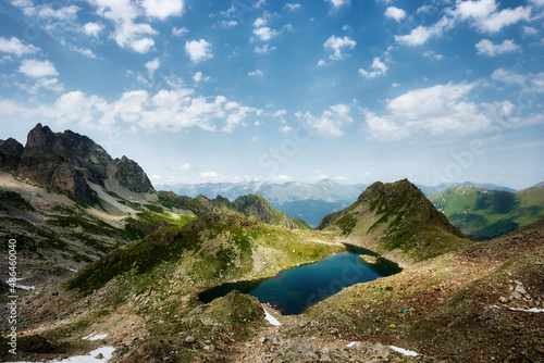 Panoramic view of turquoise Lake with surrounding sharp peaks mountains in the valley during sunny summer day