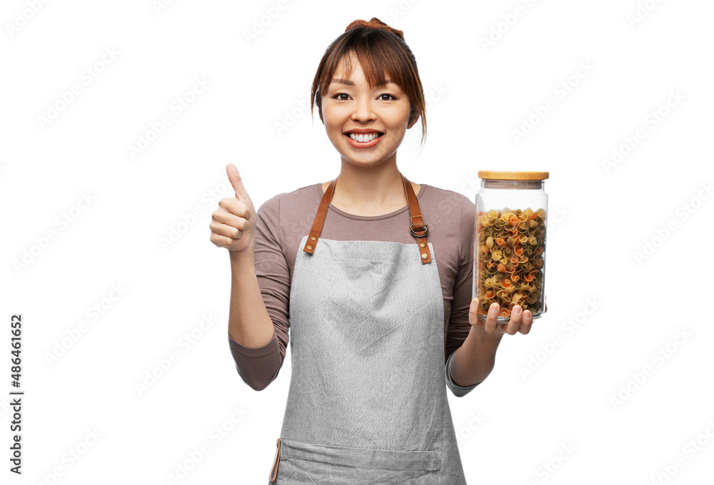 cooking, culinary and people concept - happy smiling woman in apron holding jar with pasta and showing thumbs up gesture over white background cooking, culinary and people concept - happy smiling woman in apron holding jar with pasta and showing thumbs up gesture over white background