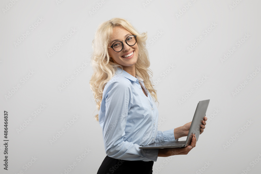 Online job. Portrait of happy businesswoman working on laptop computer and smiling at camera, light grey background
