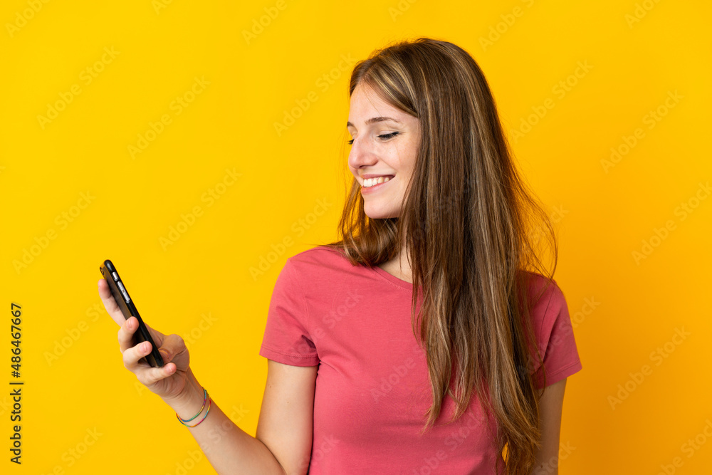 Young woman using mobile phone isolated on yellow background with happy expression Young woman using mobile phone isolated on yellow background with happy expression