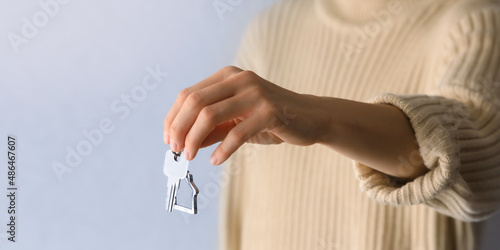 Female hand holding house key, real estate agent.