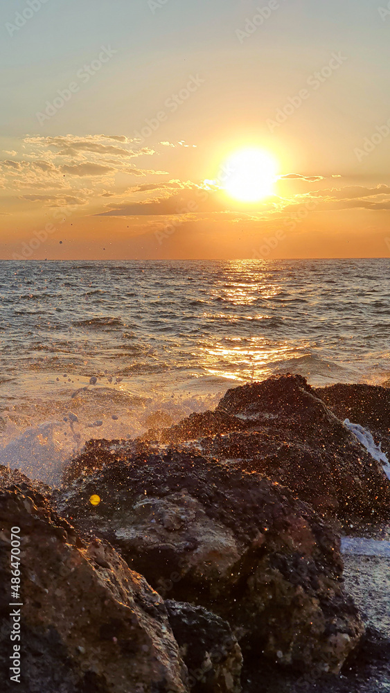 Colorful sunset with large sun under the sea waves.