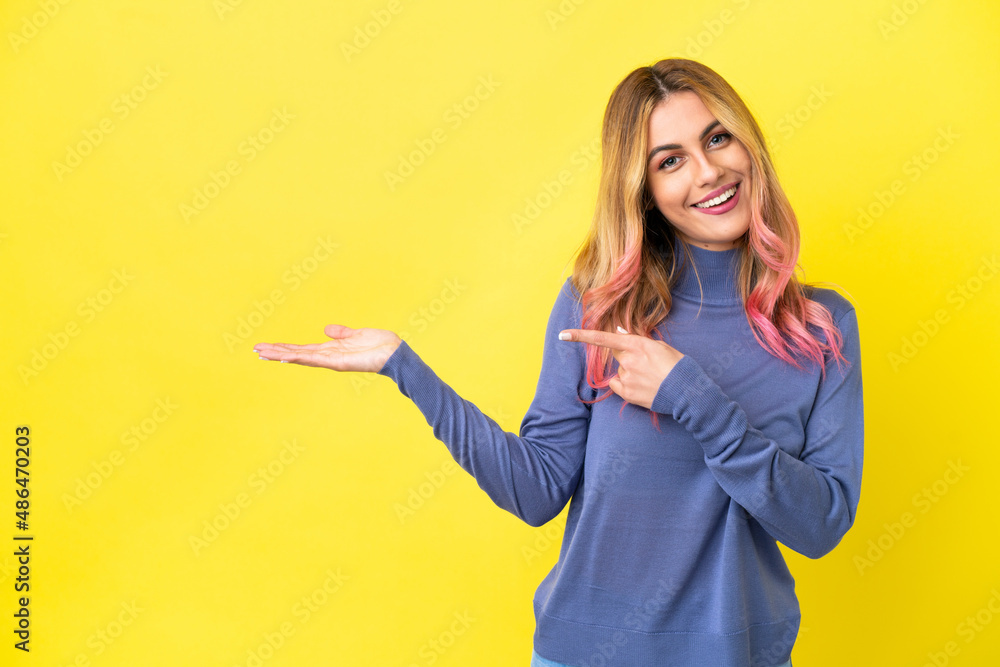 Young woman over isolated yellow background holding copyspace imaginary on the palm to insert an ad Young woman over isolated yellow background holding copyspace imaginary on the palm to insert an ad