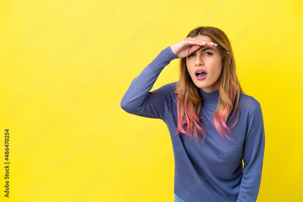 Young woman over isolated yellow background looking far away with hand to look something Young woman over isolated yellow background looking far away with hand to look something
