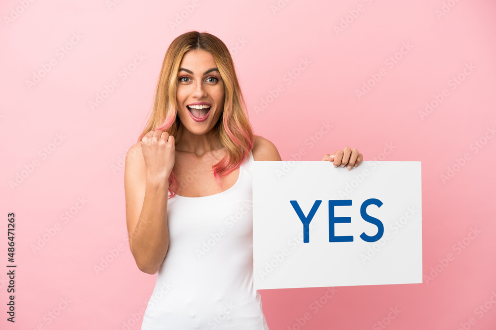 Young woman over isolated pink background holding a placard with text YES Young woman over isolated pink background holding a placard with text YES