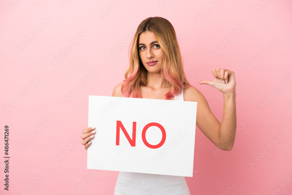 Young woman over isolated pink background holding a placard with text NO Young woman over isolated pink background holding a placard with text NO