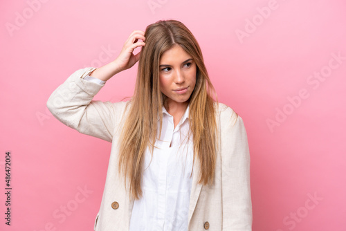 Young caucasian woman isolated on pink bakcground having doubts while scratching head