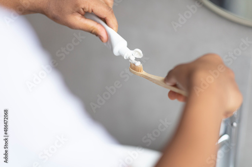 Daily dental care. Male hands pouring toothpaste on toothbrush, enjoying dental hygiene, closeup