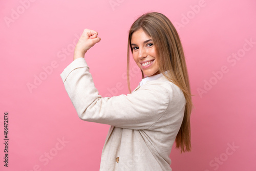 Young caucasian woman isolated on pink bakcground doing strong gesture