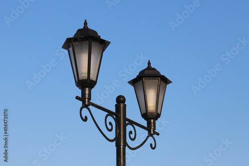 Beautiful lighting lamppost on a blue sky background. © EVGENY