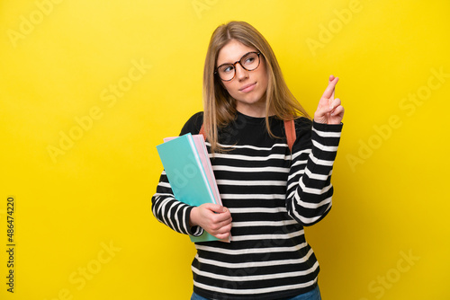 Young student woman isolated on yellow background background with fingers crossing and wishing the best