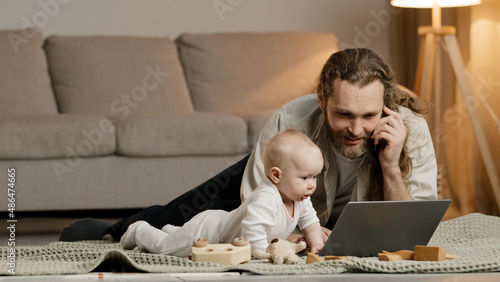 Single father adult stressed business man multitasking dad lying on floor at home with little daughter talking on phone with laptop baby crawling typing interferes disturb work infant child problems