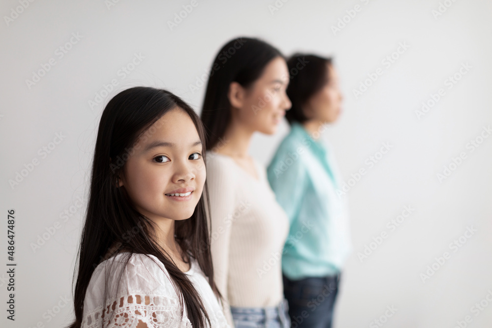 Cheerful little Asian girl with her mother and grandmother posing on white studio background, copy space Cheerful little Asian girl with her mother and grandmother posing on white studio background, copy space