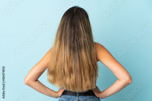 Young caucasian woman isolated on blue background in back position